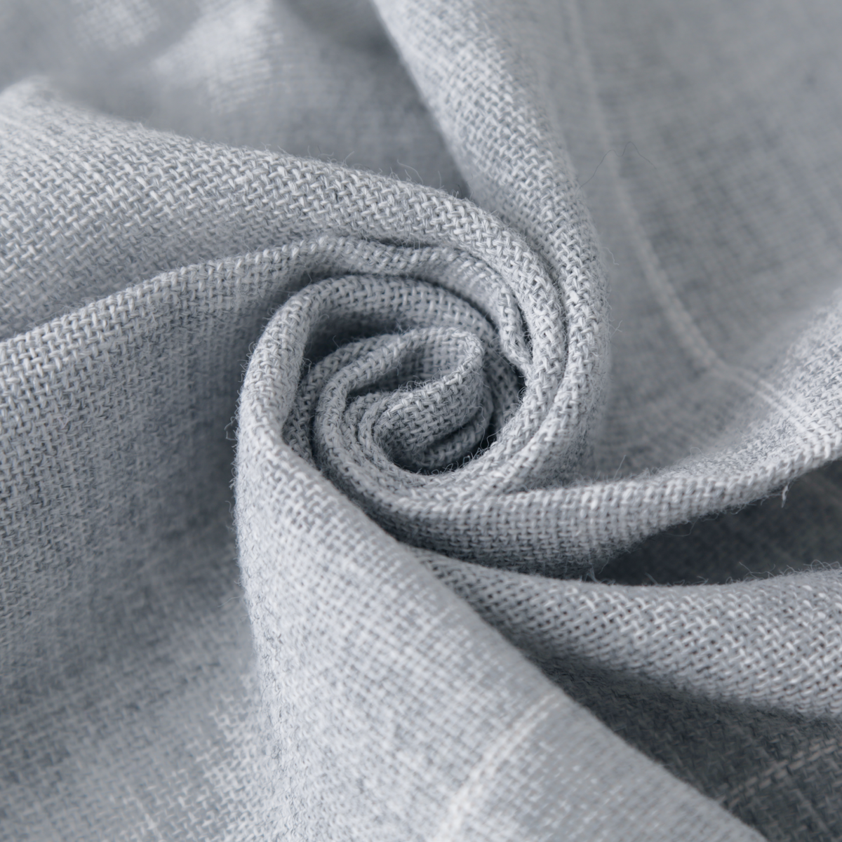 A Craftphilia premium tufting cloth close-up of light gray woven fabric arranged in a spiral swirl, showing the material texture and color.