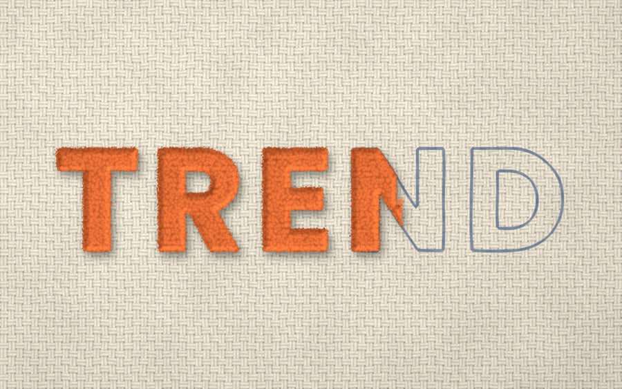The word TREND tufted in orange yarn on tufting cloth, with the last letters still drawn in outline, waiting to be tufted